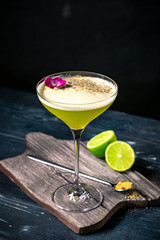 Classic alcoholic cocktail Daiquiri with lime and kiwi in a glass on a black background. Tropical vermouth with green fruit.