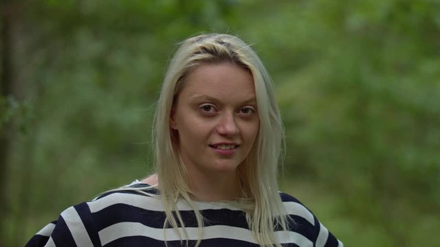 Blonde girl in zebra shirt smiling and looking straight into the camera. Slow motion.