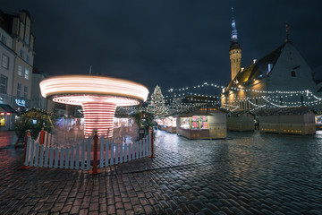 Fototapeta na wymiar European Christmas market in night in Tallinn old town square with big Christmas tree and Merry-go-round