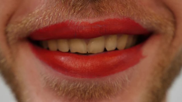 Extra close up of man's lips with red lipstick. Man with bearded face and red lipstick on lips. Travesty makeup concept