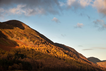 Naklejka premium Majestic vibrant Autumn Fall landscape Buttermere in Lake District with beautiful early morning sunlight playing across the hills and mountains