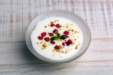 a bowl of curd with  pomegranate sees and chat masala