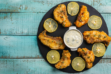 Exposition of cooked fish on black plate and wooden table, very tasty food.
