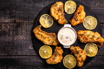 Exposition of cooked fish on black plate and wooden table, very tasty food.
