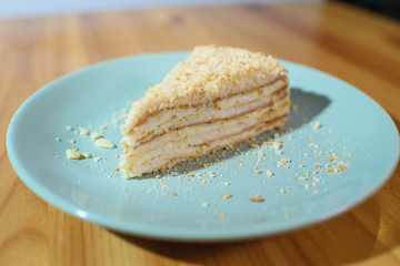 Slice of Napoleon cake on a large light wooden table
