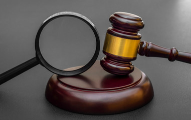 Judge's gavel with magnifying glass on black.