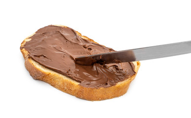 Piece of bread with chocolate butter and knife on white background.