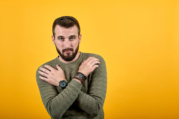 Caucasian unshaven pretty man over isolated orange background wearing casual green clothes keeping hands crossed on chest, looking at camera