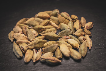 Close up view of cardamom seeds in black slate background. 