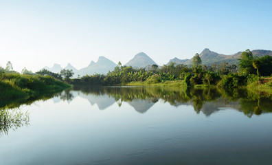 The image of a quiet lake reflecting the mountain range, not very large. Natural atmosphere in the...