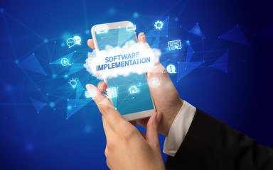 Female hand holding smartphone with SOFTWARE IMPLEMENTATION inscription, cloud technology concept