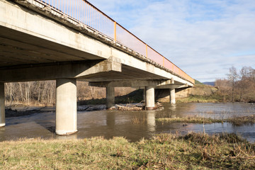 Reinforced concrete bridge over a small river. Autumn landscape.