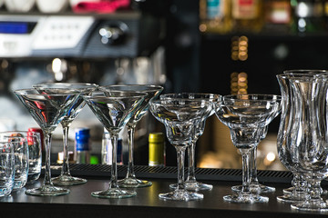 Glasses for a margarita, martini, grog and liqueur on a bar at restaurant, against the bar bar wall...