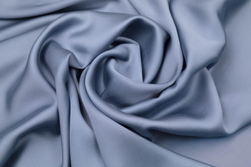 Naklejka na ściany i meble The blue satin fabric is laid out on the table . Material has Soft folds of a drapery
