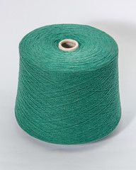 Green bobbin of yarn on a white background.Textile reel on isolated white background.