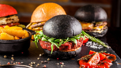 American food concept. Black bun burger with the words meat and burger, with veal tartar, tomato and arugula. copy space