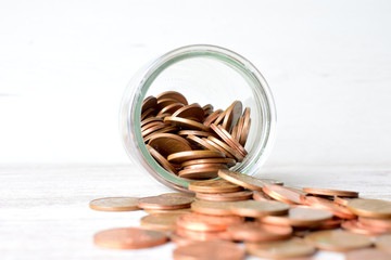 Euros, monedas en un frasco tumbado, esparcidas las monedas sobre la mesa