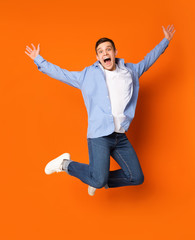 Funny portrait on teen guy jumping on orange background