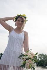 beautiful bride with wedding bouquet standing on a boat and posing for the photographer near the river
