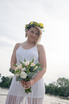 beautiful bride with wedding bouquet standing on a boat and posing for the photographer near the river