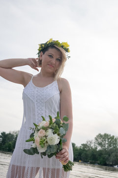 beautiful bride with wedding bouquet standing on a boat and posing for the photographer near the river