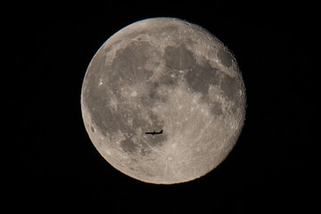 Passenger plane flying in front of full moon at night, Germany