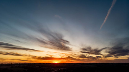 Sunset over a rural countryside with a country road going to the horizon