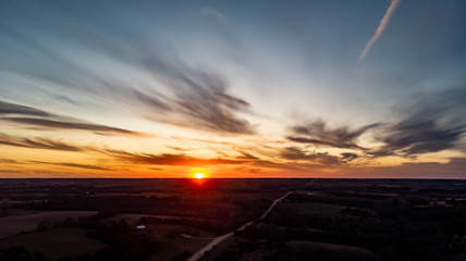 Fototapeta premium Sunset over a rural countryside with a country road going to the horizon