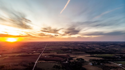 Sunset over a rural countryside with a country road going to the horizon