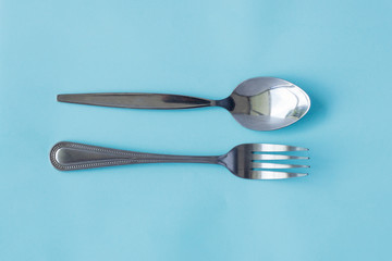 Top view close up of Spoon with fork on blue pastel background. Flat lay, Copy space. Minimal concept