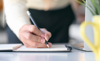 Closeup view of man hand writing on notebook with pencil.