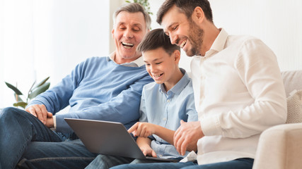 Fototapeta premium Boy Using Laptop Sitting Between Father And Grandpa At Home