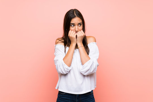 Young woman over isolated pink background nervous and scared putting hands to mouth