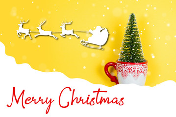 Fototapeta na wymiar Christmas tree in a holiday mug with text Merry Christmas on a yellow background