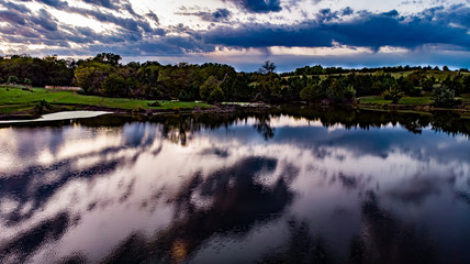 Golden hour sunset over a pond with clouds, sky, and trees