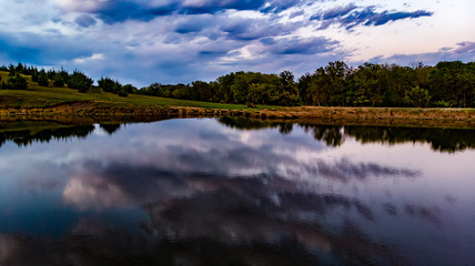 Golden hour sunset over a pond with clouds, sky, and trees