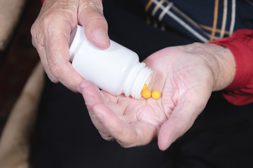 Hands of an old woman holding a white jar with omega-3 medicine capsules and vitamins. Health concept supplements pills and vitamins