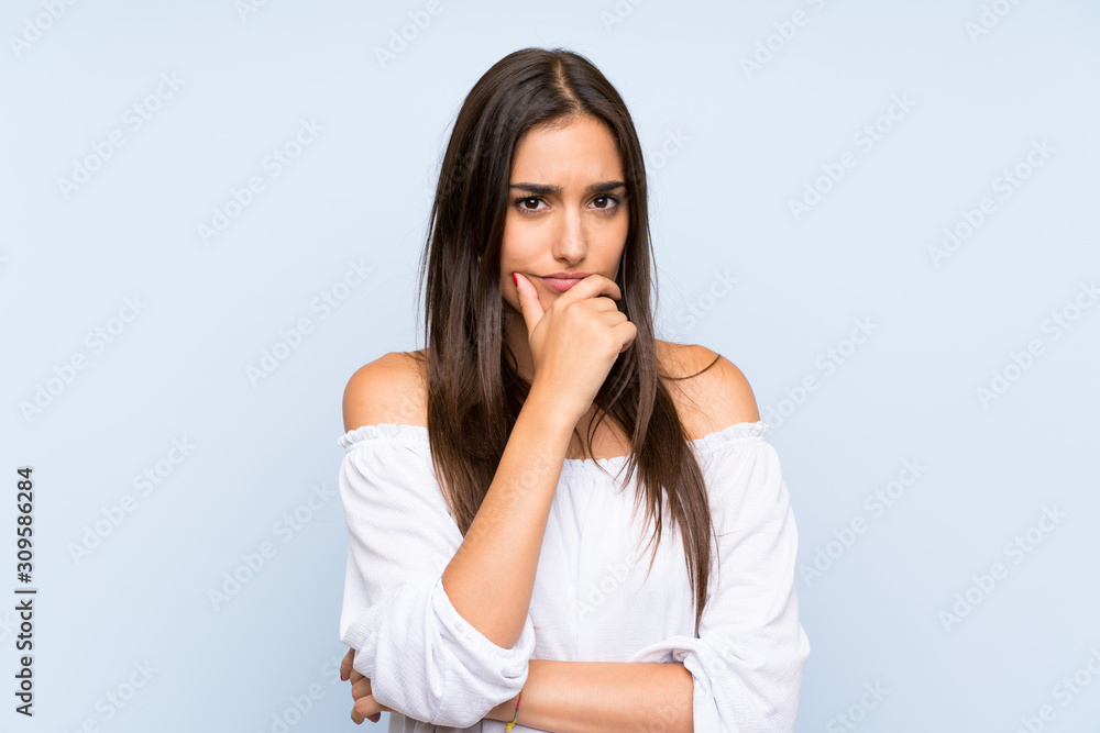 Wall mural young woman over isolated blue background thinking an idea