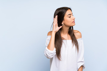 Young woman over isolated blue background listening something