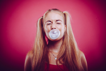 cute blond teen with ponytail blowing up chewing bubble gum