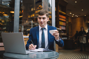 Young businessman enjoying coffee and taking notes