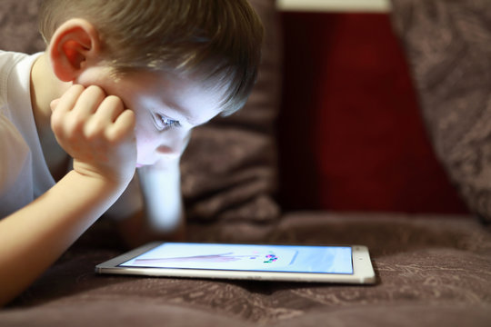 Child with tablet on sofa