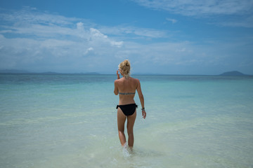 Beautiful young female in bikini on gorgeous sandy beach enjoying summer time vacation