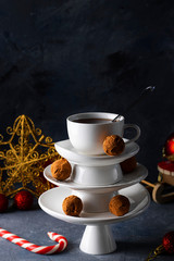 Obraz na płótnie Canvas White saucer pyramid with cup of tea on top, like Christmas tree with decorated with sweet chocolate truffles, dark background Creative concept, restaurant, wallpaper postcard, Xmas New Year, Vertical