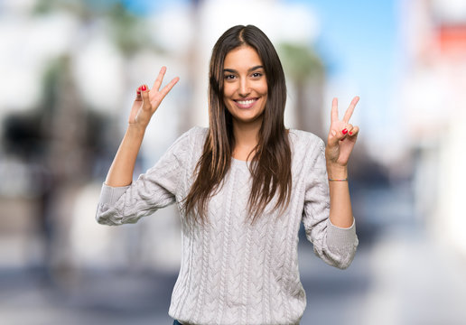 Young Hispanic Brunette Woman Showing Victory Sign With Both Hands At Outdoors