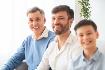 Elderly Man With Middle-Aged Son And Grandson Sitting On Couch