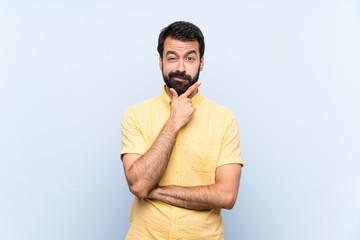 Fototapeta premium Young man with beard over isolated blue background thinking