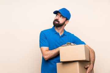Delivery man with beard over isolated background with confuse face expression