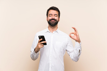 Young man with beard holding a mobile in zen pose