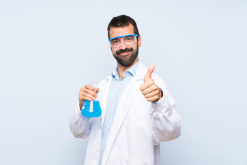 Young scientific holding laboratory flask over isolated background with thumbs up because something good has happened